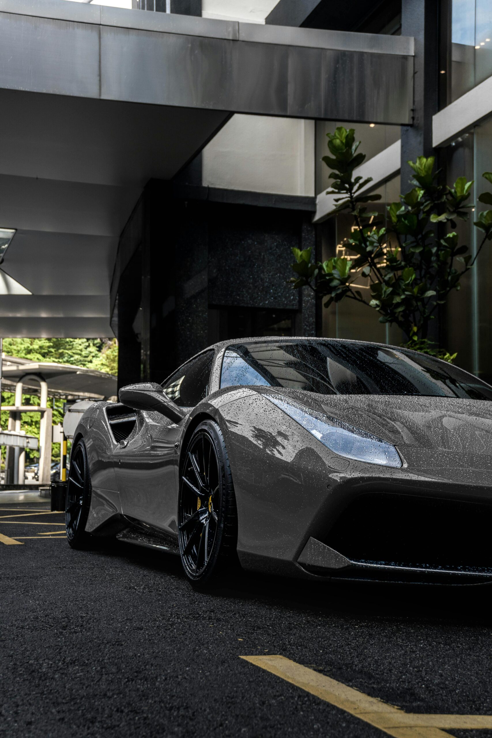 A shiny sportscar parked under a modern urban structure, showcasing luxury and design.