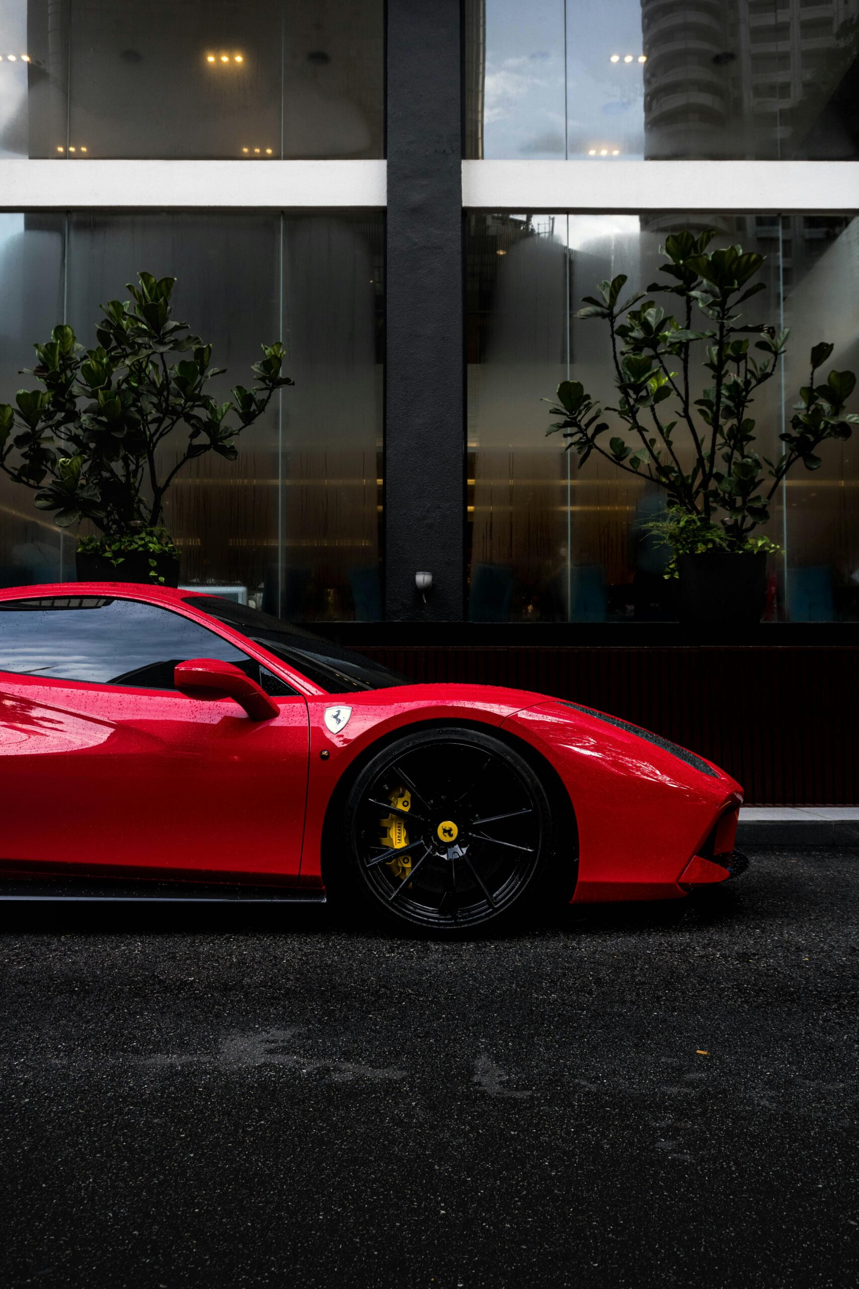 Side profile of a sleek red sports car parked on an urban road.