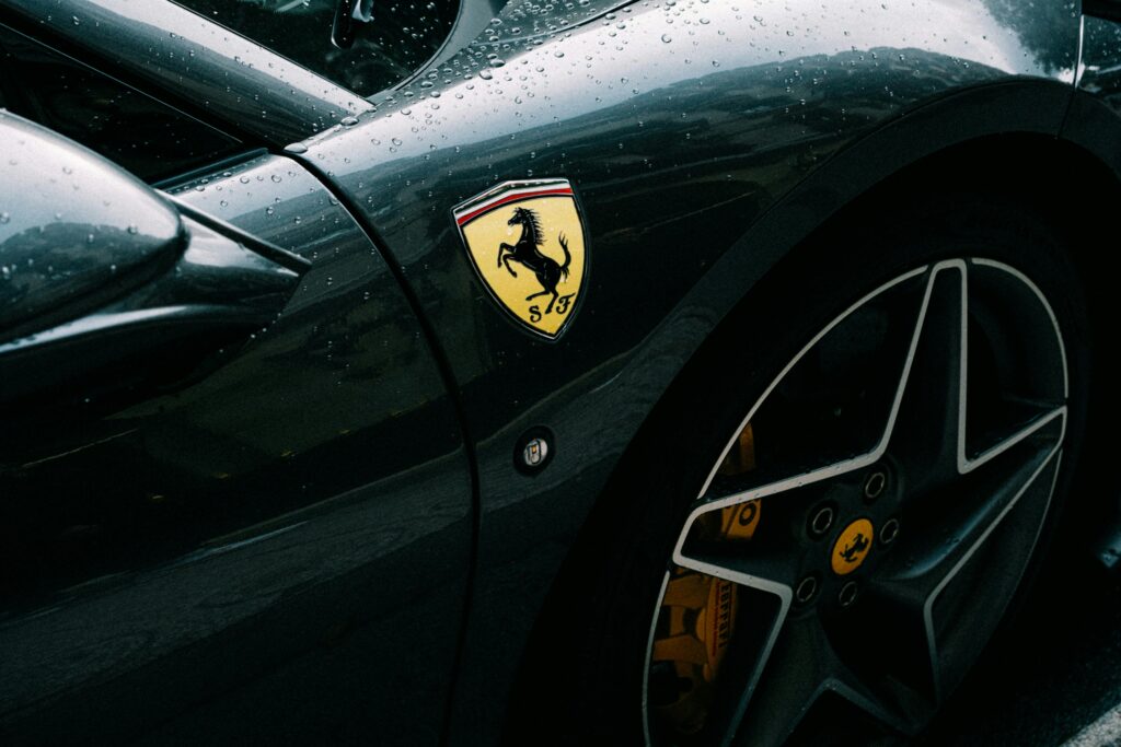 Detailed shot of a Ferrari fender with emblem and raindrops, showcasing luxury and design.